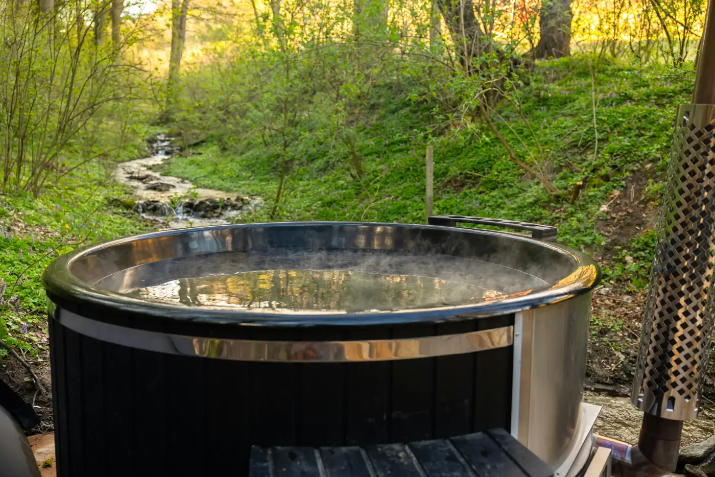 De buitenjacuzzi dampt aan de rand van het bos.